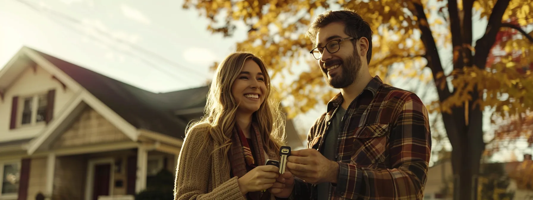 a couple standing outside a charming house in farmington hills, smiling happily as they hold a set of keys, signifying a successful home purchase.